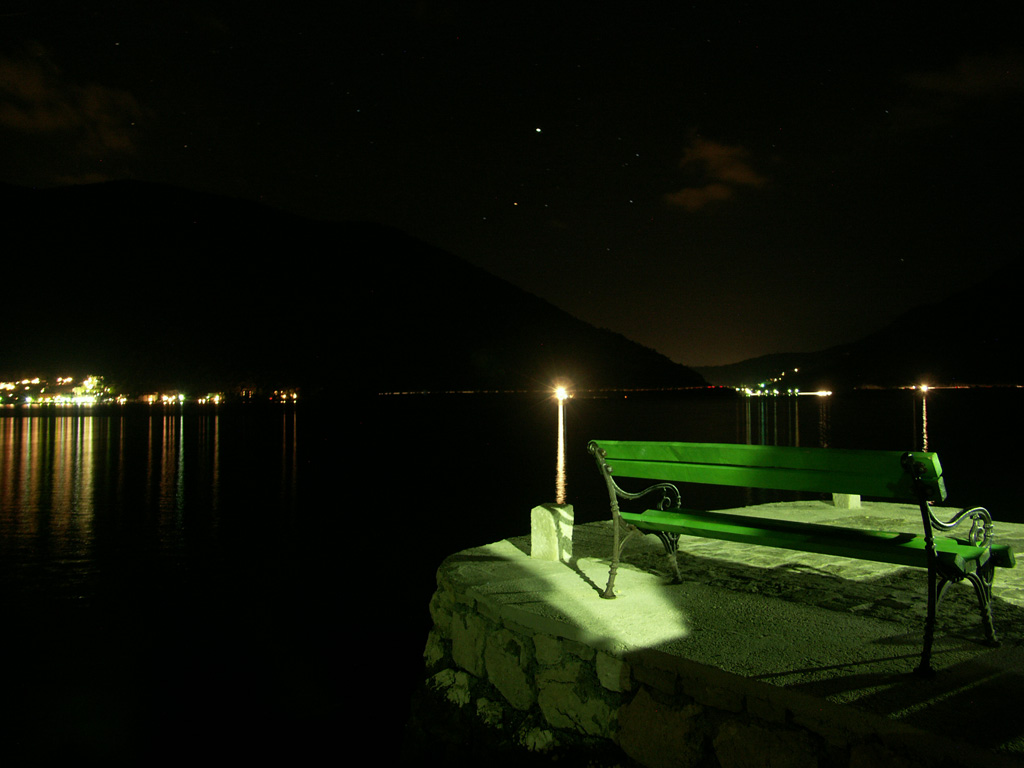 A green bench in the middle fo the night