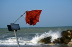 un mare scosso dal vento con un ombrello a banderuola in primo piano